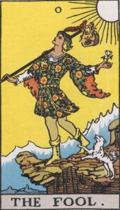 The Fool tarot card depicting a young man standing on the edge of a cliff, dressed in colorful attire with flowers. He carries a small bag and a flower while a dog playfully jumps at his feet. The sun shines brightly in the background, symbolizing new beginnings, adventure, and potential.